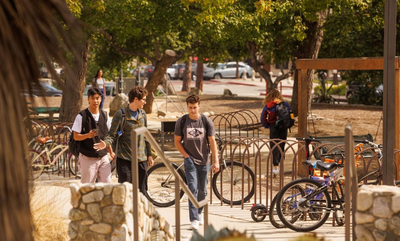 Three students walk together past a bike rack on campus.