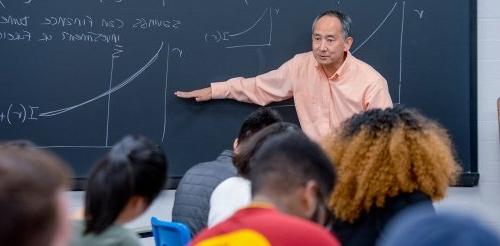 professor linu yamane points to writing on a blackboard