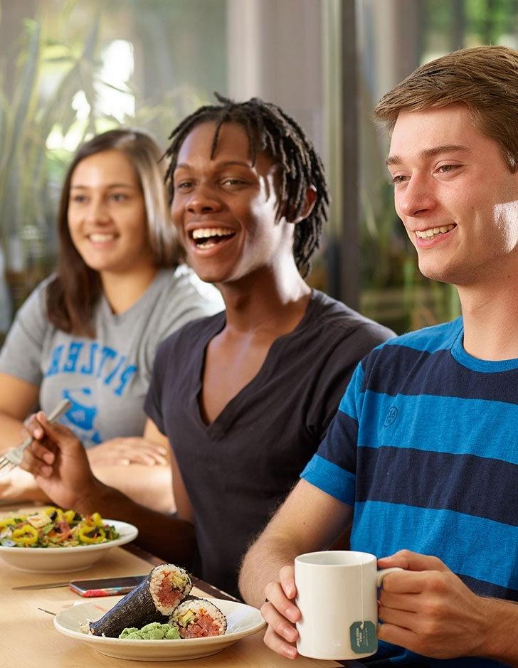 three students eat lunch in the dining hall